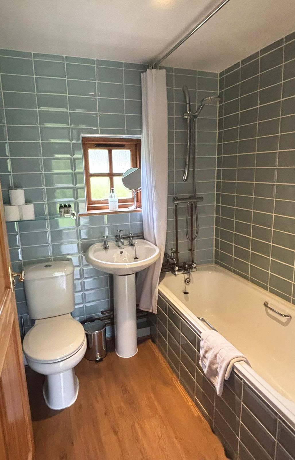 The tiled bathroom in the Bothy at Glen Dessary with a bath and shower