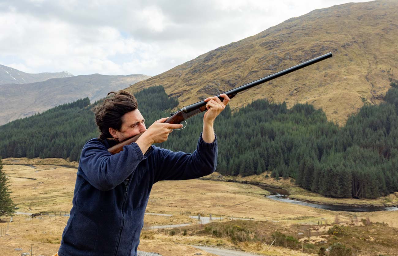 A gun mounting a shotgun for clays above the glen at Glen Dessary Estate