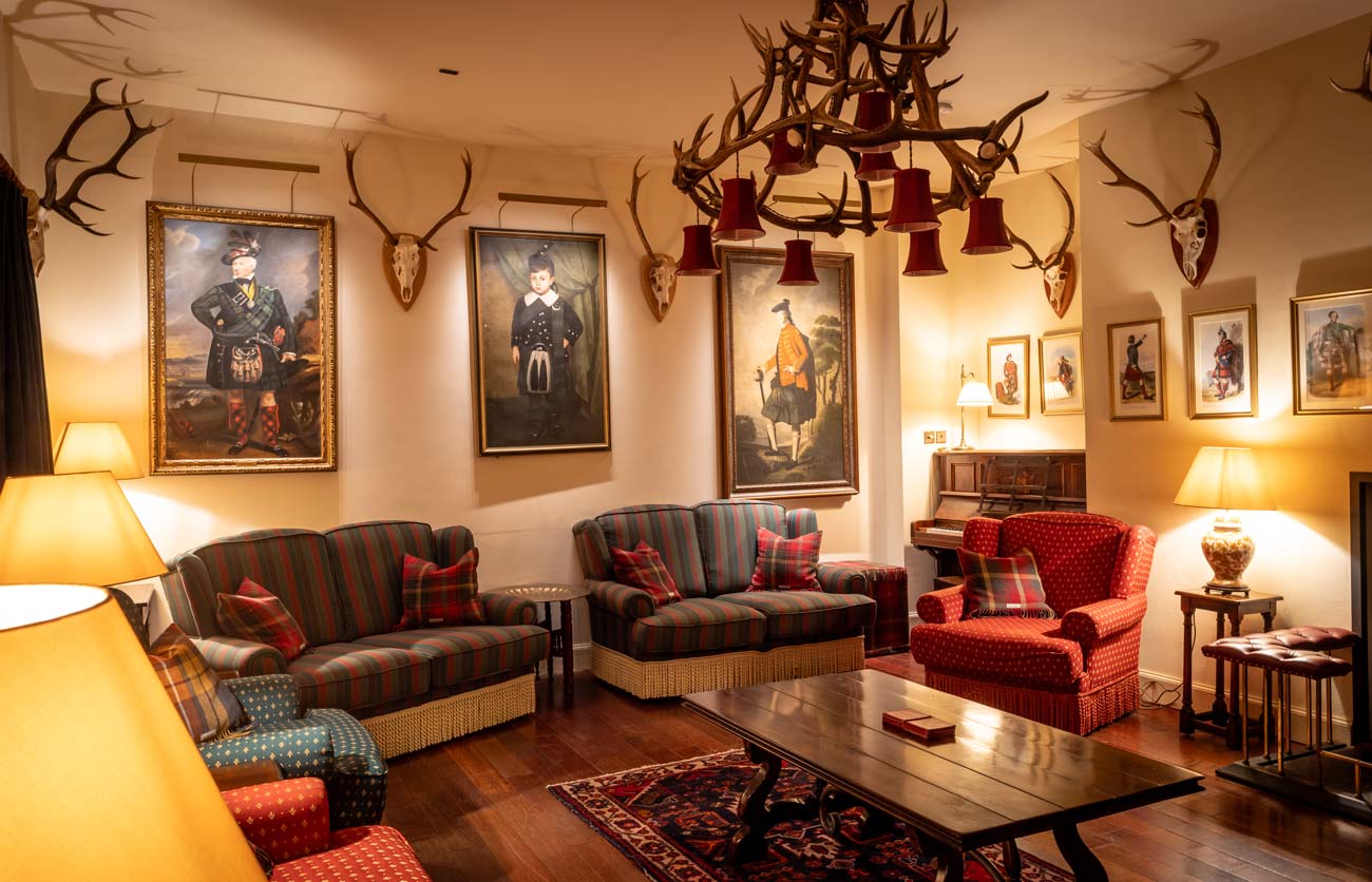 The drawing room at Glen Dessary Lodge with antler chandelier, Highland portraits and open fire